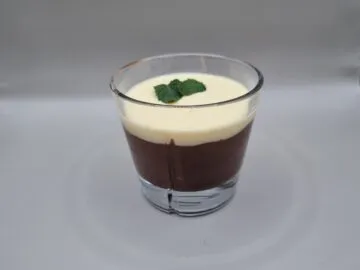Sjokoladepudding av egg med et tynt lag med vanilje servert i et whiskyglass. Grå bakgrunn.
